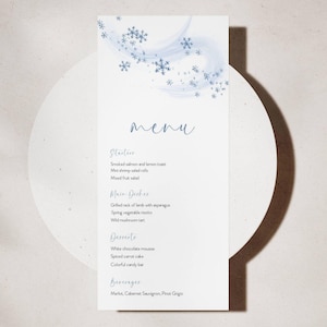 Peut inclure: Une carte de menu blanche avec un motif de flocons de neige bleus en haut. Le mot "menu" est écrit en cursive. Le menu propose des entrées, des plats principaux, des desserts et des boissons. Les plats sont écrits dans une police simple et lisible.