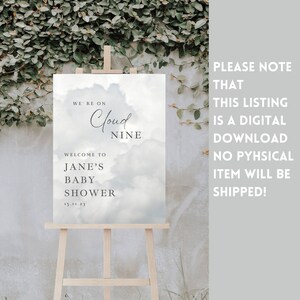May include: A printable baby shower sign with a blue and white cloudy background. The text reads "We're on Cloud Nine. Welcome to Jane's Baby Shower 15.11.23".