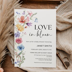 May include: A baby shower invitation with the words "LOVE in bloom" in black script. The invitation features a watercolor floral design in pink, purple, yellow, and blue. Details include the honoree's name, date, time, and venue.