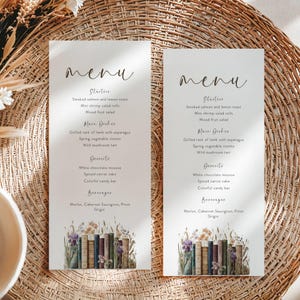 May include: Two elegant menu cards with a watercolor illustration of books and flowers at the bottom. The menu includes starters, main dishes, desserts, and beverages. The word "Menu" is written at the top in a script font.