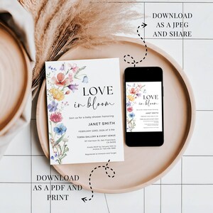 May include: A baby shower invitation with floral watercolor design. The invitation reads "LOVE in bloom" and includes event details. A smartphone displays the invitation. The invitation is on a wooden tray.