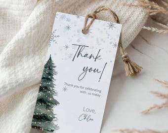Könnte beinhalten: Ein weißes Geschenk-Etikett mit einer Aquarell-Illustration eines Weihnachtsbaums und Schneeflocken. Das Etikett trägt die Aufschrift "Thank you!" mit zusätzlichem Text und einem Namen. Eine Schlaufe aus Naturfaden ist angebracht.