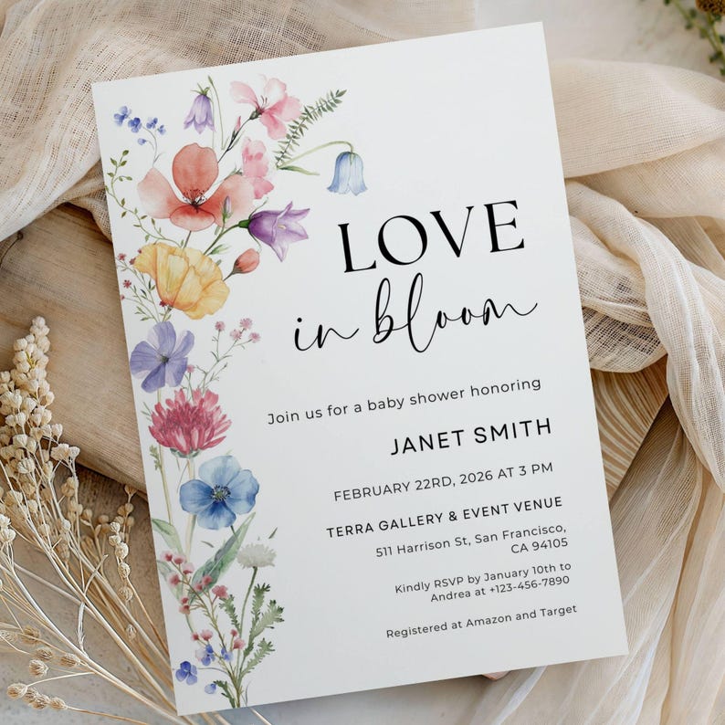May include: A baby shower invitation with the words "LOVE in bloom" in black script. The invitation features a watercolor floral design in shades of pink, blue, yellow, and purple. Details include the honoree's name, date, time, and location.