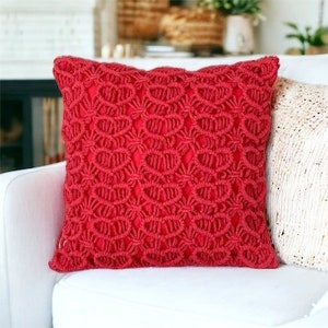 May include: Red throw pillow with a crocheted design. The pillow is made of a thick, textured fabric and has a square shape.