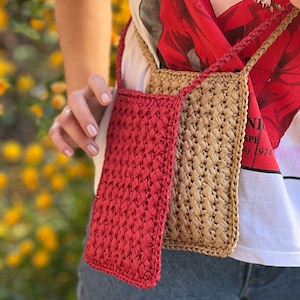 May include: Two crocheted bags, one red and one beige, worn as a crossbody bag. The bags are made of woven straw-like material.
