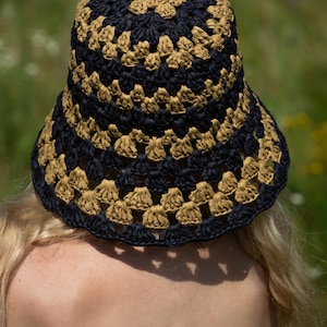 May include: A black and tan crocheted bucket hat with a wide brim.