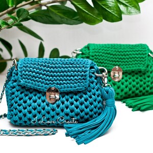 Puede incluir: Dos bolsos de mano de crochet con correas de cadena plateadas y borlas. El bolso de mano de la izquierda es azul turquesa y el bolso de mano de la derecha es verde. Ambos bolsos de mano tienen un cierre plateado.