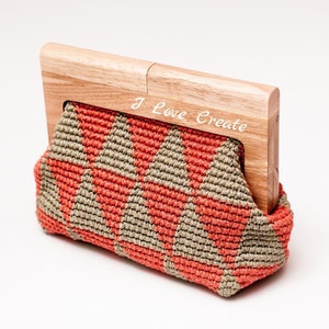 Op de afbeelding: Handgemaakte clutch met een houten frame. De macram&eacute; tas heeft een geometrisch patroon in koraal en beige. Het houten frame is gegraveerd met de woorden "I Love Create".