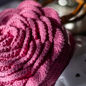 May include: A pink crocheted rose flower with a white tag that says "THANK you".
