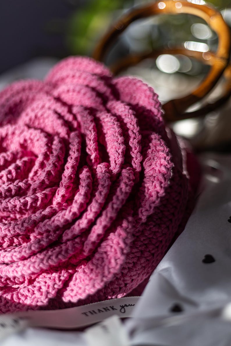 May include: A pink crocheted rose flower with a white tag that says "THANK you".