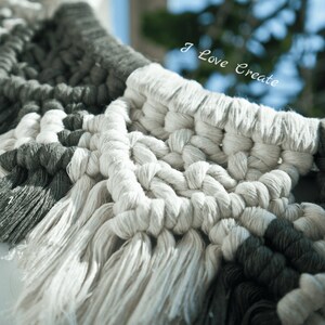 May include: Close-up of a macrame wall hanging with a white and gray color scheme. The macrame is made with thick cords and has a geometric pattern. The text "I Love Create" is visible in the background.