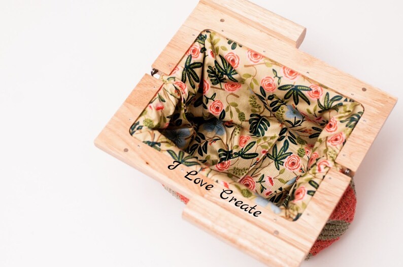 Op de afbeelding: Een houten mand met een bloemenpatroon stoffen voering. De stof heeft roze rozen, groene bladeren en blauwe accenten op een beige achtergrond. De tekst "I Love Create" is zichtbaar aan de zijkant.