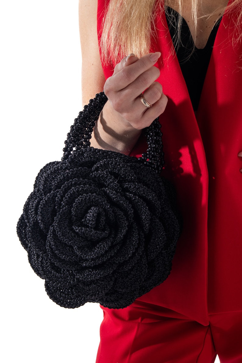 May include: A black crocheted rose-shaped handbag with a black beaded handle.