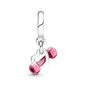 May include: A silver charm featuring a pink dumbbell within a heart-shaped frame. The charm is designed to be attached to a bracelet or necklace.