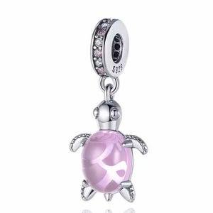 May include: A silver charm in the shape of a turtle with a pink crystal shell. The charm has a silver loop at the top and is decorated with small clear and pink crystals.