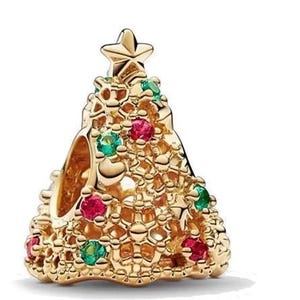 May include: A gold charm shaped like a Christmas tree, decorated with red and green gemstones. The charm features a delicate, intricate design.