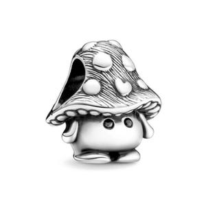 May include: A silver mushroom charm with a dotted cap. The mushroom has a smiling face with two black eyes and small arms and feet. The charm is designed to be used as a pendant or bracelet charm.