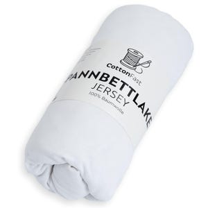 May include: A rolled white fitted sheet with a label. The label reads "CottonFast," "Spannbettlaken Jersey," and "100% Baumwolle." A graphic of a thread spool is also on the label. The sheet is made of jersey.