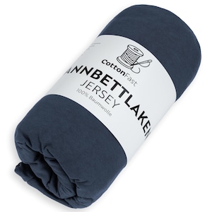 May include: Rolled navy blue jersey sheet set. The label reads "CottonFast" with a spool and needle graphic. The text on the label also reads "Jannbettlaken Jersey 100% Baumwolle".