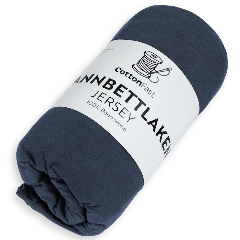 May include: Rolled navy blue jersey sheet set. The label reads "CottonFast" with a spool and needle graphic. The text on the label also reads "Jannbettlaken Jersey 100% Baumwolle".