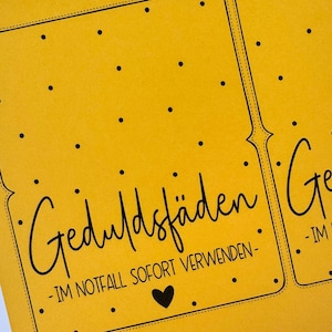 K&ouml;nnte beinhalten: Nahaufnahme einer gelben Karte mit schwarzem Text und einem Herz. Die Karte lautet "Geduldsf&auml;den - IM NOTFALL SOFORT VERWENDEN -" in einer handschriftlichen Schriftart. Kleine schwarze Punkte sind &uuml;ber die Oberfl&auml;che der Karte verstreut.