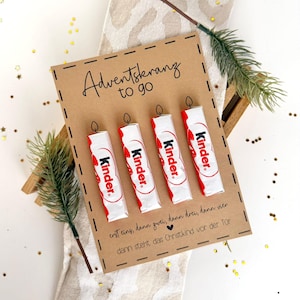 Könnte beinhalten: Eine braune Karte mit dem Text "Adventskranz to go" und vier Kinder-Schokoriegeln, die wie Kerzen angeordnet sind. Die Karte trägt den Text "erst eins, dann zwei, dann drei, dann vier, dann steht das Christkind vor der Tür".