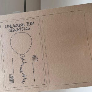 Pode incluir: Um cart&atilde;o castanho com uma borda preta e o texto "Einladung zum Geburtstag" (Convite de anivers&aacute;rio) e um gr&aacute;fico de um bal&atilde;o. O cart&atilde;o tem espa&ccedil;os em branco para escrever a data, a hora e o local da festa de anivers&aacute;rio.