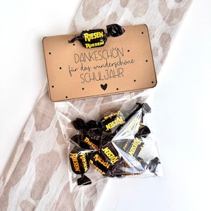 Könnte beinhalten: Eine braune Karte mit dem Text "DANKESCHÖN. für das wunderschöne SCHULJAHR" und einem Herz. Eine durchsichtige Plastiktüte gefüllt mit Schokoladenbonbons mit gelben Verpackungen, auf denen "RIESEN" steht.