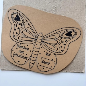 K&ouml;nnte beinhalten: Eine braune Papier-Einladung in Form eines Schmetterlings mit schwarzen Umrissen und Punkten. Der Text "Einladung zum Geburtstag" steht auf dem linken Fl&uuml;gel. Der rechte Fl&uuml;gel tr&auml;gt die Aufschrift "Wo?" und "Wann?"