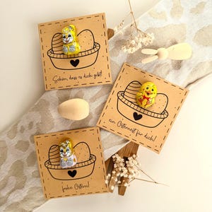 May include: Easter gift cards with chocolate bunny and chick figures. Each card features a basket design with eggs and a heart. The cards have German text: "Schön, dass es dich gibt!", "frohe Ostern!", and "ein Osternest für dich!"
