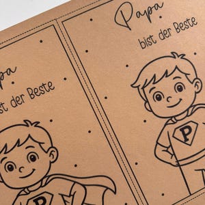 May include: Two brown cards with black line art. Each card features a cartoon superhero boy with a cape and the letter "P" on his shirt. The text "Papa bist der Beste" is written in script above the boy.
