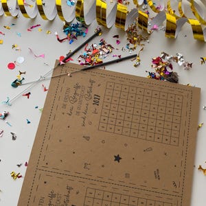 K&ouml;nnte beinhalten: Eine braune Papierkarte mit einem Wortsuchr&auml;tsel f&uuml;r 2027 und dem deutschen Text Die ersten drei Begriffe die du entdeckst sind deine Botschaft f&uuml;r 2027, umgeben von goldenen Luftschlangen und buntem Konfetti.