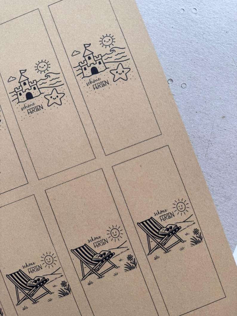 May include: Brown paper bookmarks with black line art illustrations. Designs include a sandcastle, a starfish, a beach chair, and a smiling sun. The text "sch&ouml;ne FERIEN" is printed on each bookmark.