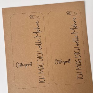May include: Two brown paper cards with rounded corners and black text. The text on the left card reads "Osterpost ICH MAG DICH volle M&ouml;hre". The text on the right card reads "Osterpost ICH MAG DICH volle M&ouml;hre".