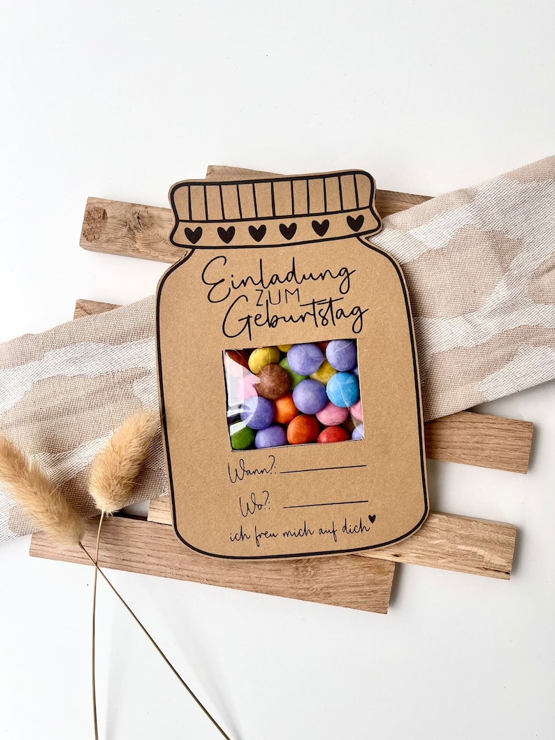 May include: A brown paper card shaped like a jar with a window showing colorful candy. The card says "Einladung zum Geburtstag" and has space to write in the date and location of the birthday party. The card also says "ich freu mich auf dich" which means "I look forward to seeing you".