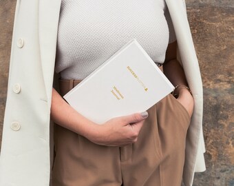 May include: A white journal with the text "Successnother" and "Wellness Journal" in gold lettering.