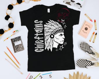 May include: Black t-shirt with a white graphic of a Native American chief and the word "Chieftains" in white. The shirt is surrounded by school supplies, including pencils, a notebook, and checkered shoes.