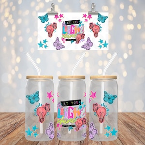 May include: Three clear glass tumblers with bamboo lids and straws, decorated with butterflies, stars, and light bulbs. The tumblers have the text "LET YOUR LIGHT SHINE". A matching print is clipped above.
