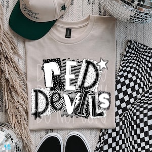 May include: A beige t-shirt with the words "RED DEVILS" in a black and white patchwork design. A beige and green baseball cap and black and white sneakers are also in the image. A black and white checkered pattern is visible.
