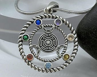May include: Silver pendant necklace with a circular design, central spiral and star motif. The pendant has colourful gemstones and crescent moon accents, suspended from a silver chain. This necklace is a piece of jewellery.