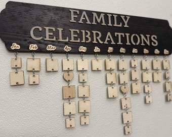 May include: A wooden calendar with the words "Family Celebrations" on it. The calendar has 12 months, each with a row of small wooden squares that can be used to mark special events. The squares are hanging from the calendar by small metal hooks.