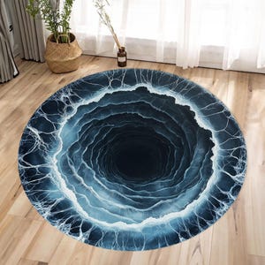 May include: A round, blue and white rug with a swirling, black hole design. The rug has a 3D effect, making it look like a hole in the ground.
