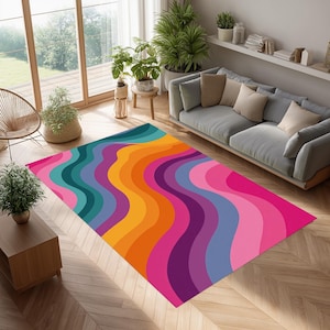 Puede incluir: Una alfombra colorida con un diseño retro ondulado. La alfombra presenta un espectro de colores, incluyendo turquesa, naranja, morado y rosa. La alfombra es rectangular y está colocada sobre un suelo de madera, añadiendo un toque de color a la habitación.