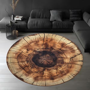 May include: A round, brown and beige area rug with a tree trunk design. The rug has a dark brown center with concentric rings of lighter brown and beige.
