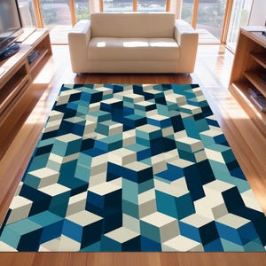 May include: A rectangular area rug with a geometric pattern of 3D cubes in shades of blue, teal, and cream. The rug is placed on a hardwood floor, with a white sofa and wooden furniture in the background.