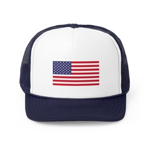Op de afbeelding: Een witte truckercap met een donkerblauw mesh achterkant en een donkerblauwe klep. De voorkant van de cap heeft een rood, wit en blauwe Amerikaanse vlag.
