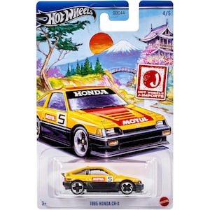 May include: A Hot Wheels die-cast model of a yellow and black 1985 Honda CR-X. The packaging features Japanese-themed artwork with a red sun, mountain, and pagoda. The car has "HONDA" and "MOTUL" branding.