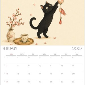 Puede incluir: Una p&aacute;gina de calendario de pared de febrero de 2027 con una ilustraci&oacute;n de un gato negro alcanzando un adorno colgante. A la izquierda, se ven un jarr&oacute;n con flores de cerezo y una peque&ntilde;a taza de t&eacute; sobre una bandeja de madera. La cuadr&iacute;cula muestra el mes.