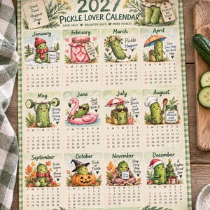 May include: A 2027 wall calendar titled Pickle Lover Calendar featuring twelve monthly grid sections. Each month displays a whimsical illustration of a pickle character in seasonal themes, accompanied by text such as In Pickles We Trust and Sour Days Brighter Days More Pickles.