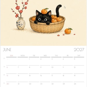Puede incluir: Una p&aacute;gina de calendario de pared de junio de 2027 con una ilustraci&oacute;n de un gatito negro sentado en una cesta tejida llena de naranjas. Una peque&ntilde;a naranja descansa sobre la cabeza del gatito. Junto a la cesta hay un jarr&oacute;n con flores rojas.